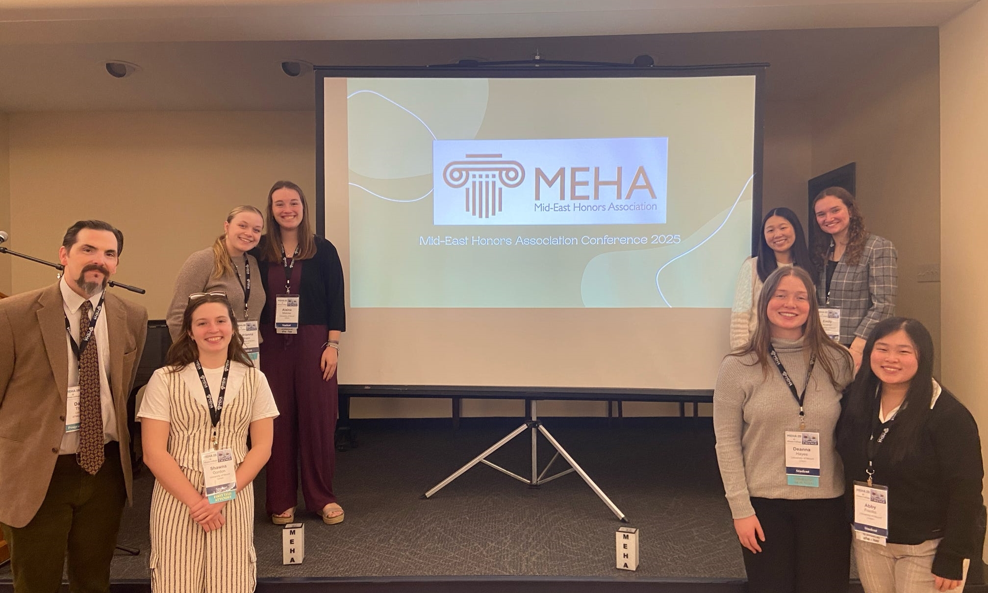 students and faculty member posing at conference