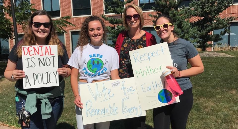 Student standing with signs about Climate