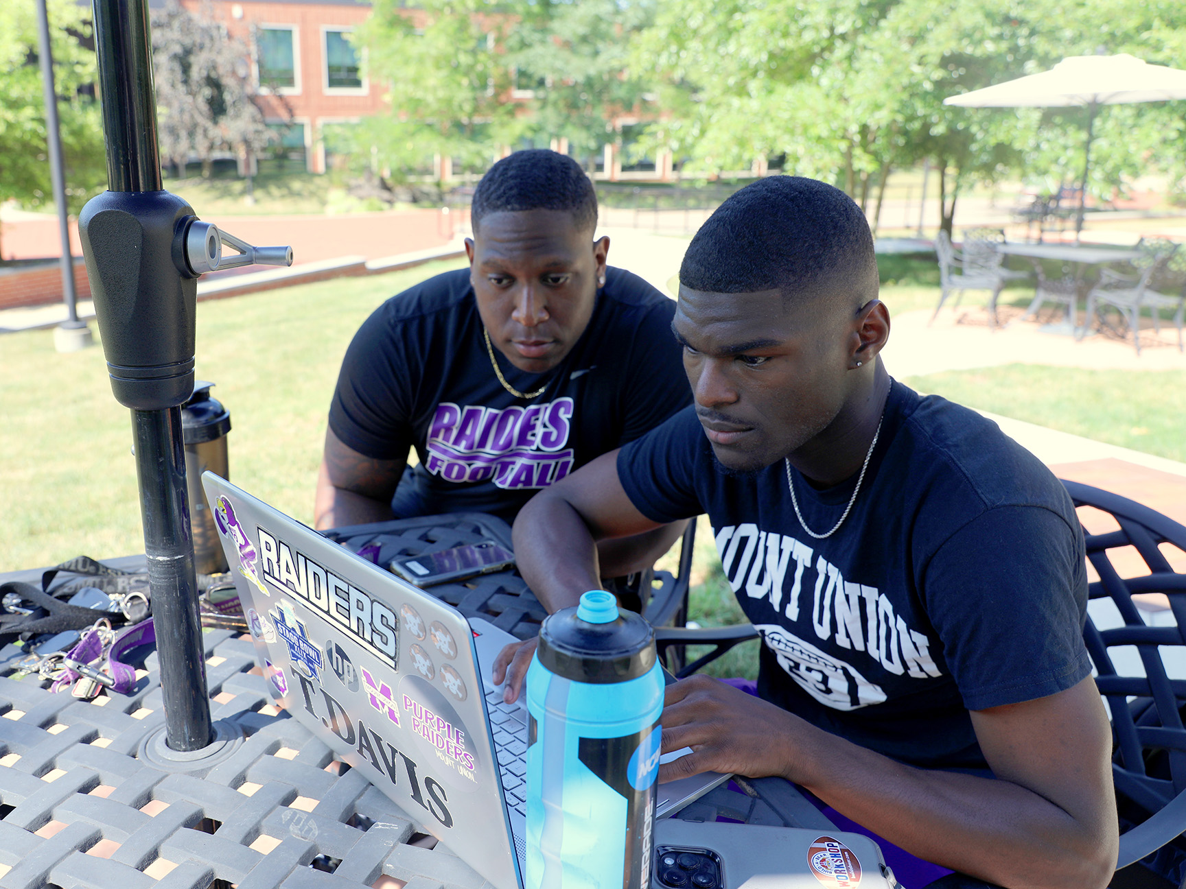 Two students looking at a laptop at an outdoor table