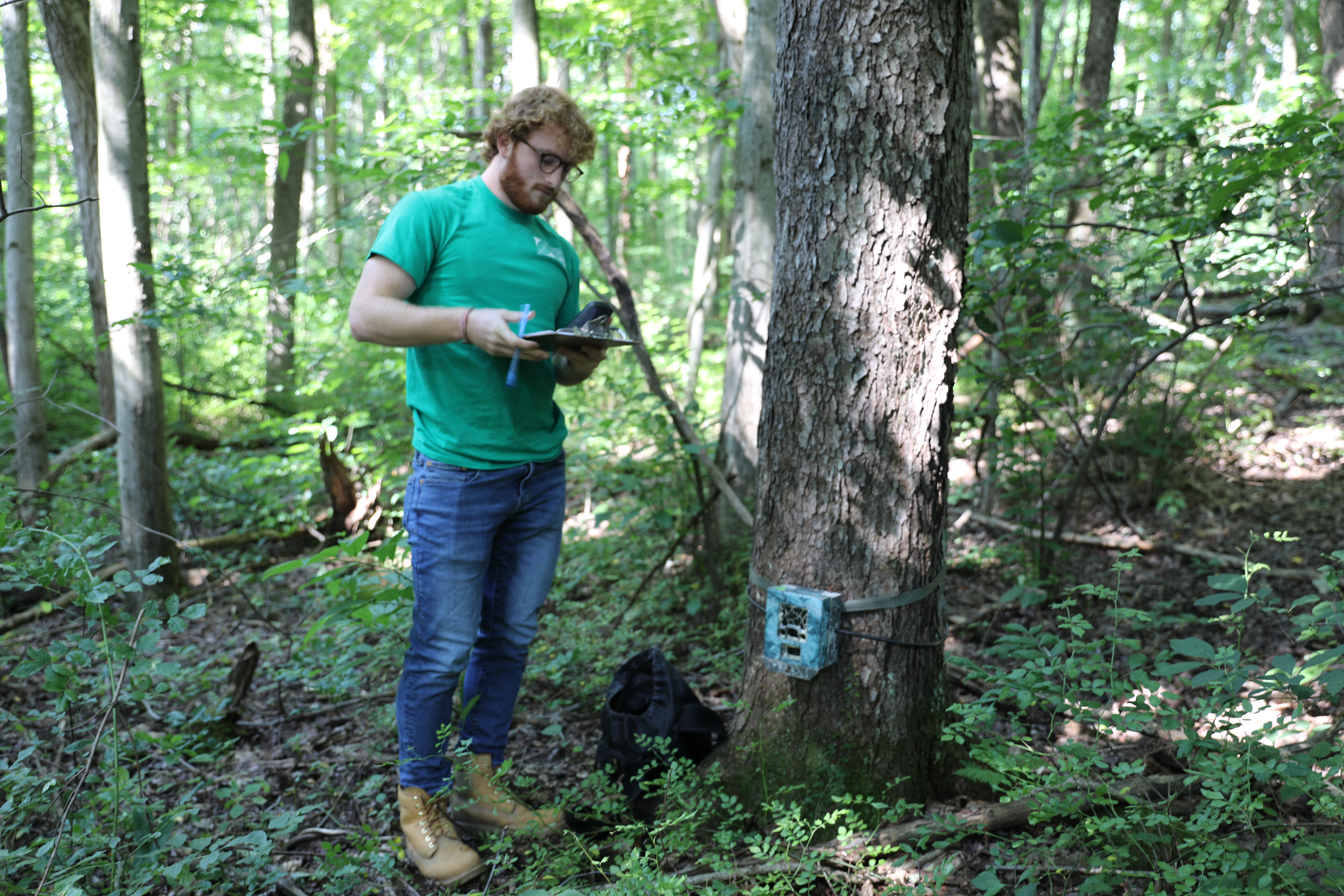 Ryland Black '22 installs trail cameras on the Nature Center trails and notes their location in a notebook.