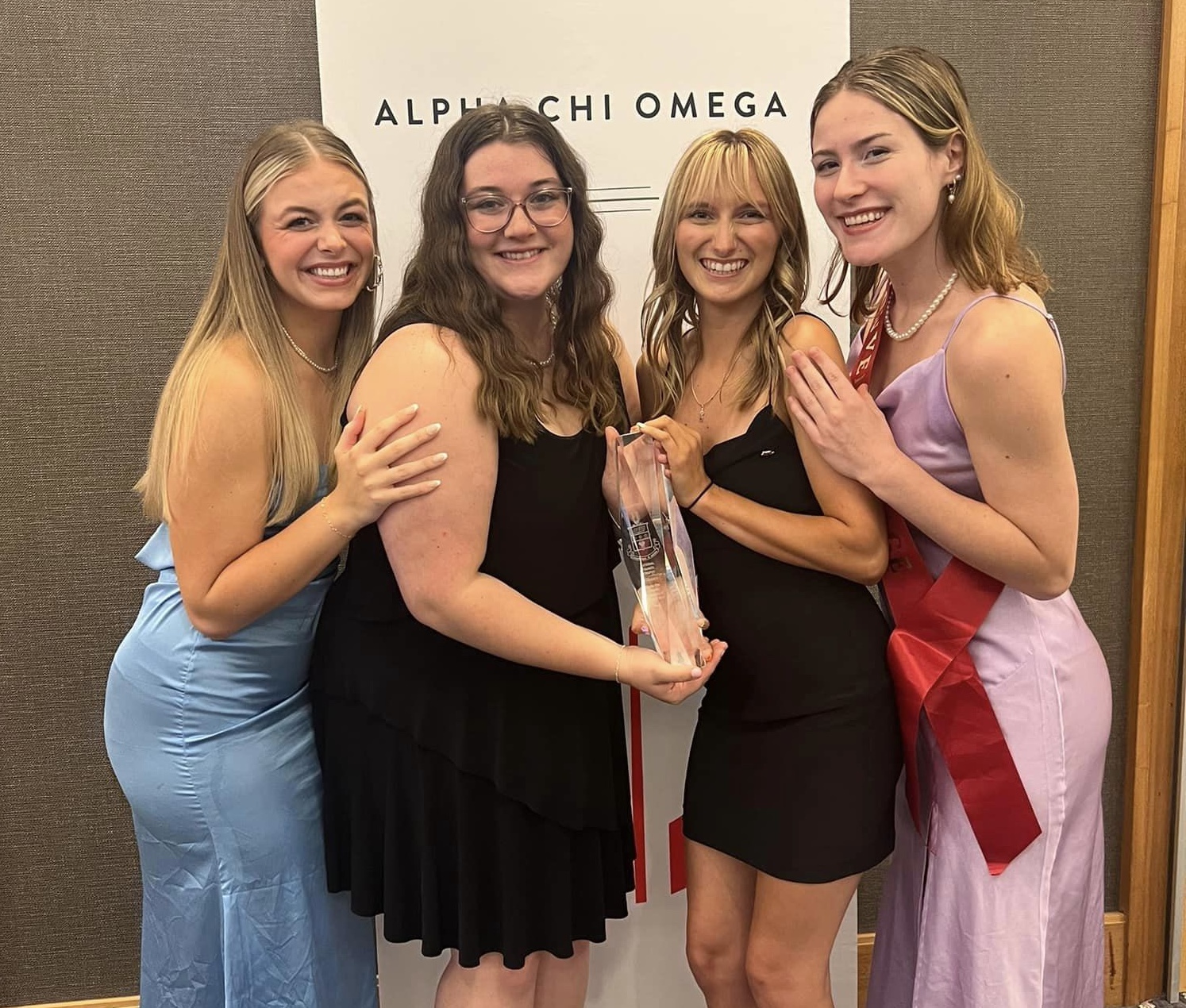 four alpha chi women posing with trophy